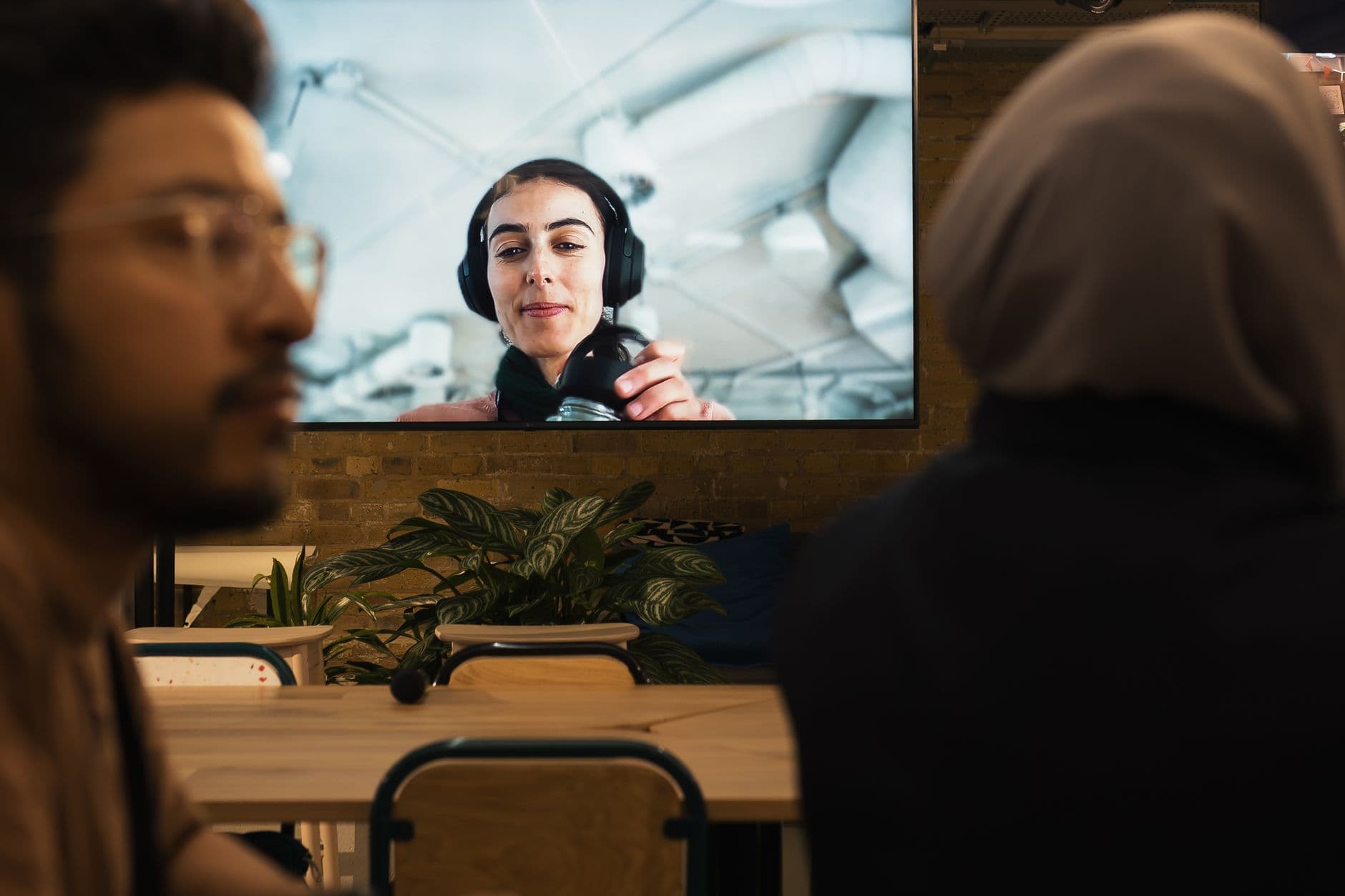 Two people participate in a virtual meeting at a stylish workspace, focused on the screen.